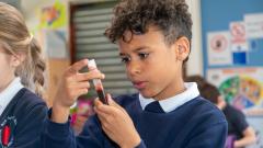 A male pupil studies a test tube in a science lesson