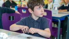 A boy experiments with magnets and iron filings during a science lesson