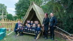 Teachers and pupils sat on the steps of an outdoor shelter having their picture taken by the local newspaper