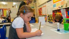 A girl uses a pencil to write notes in her work book