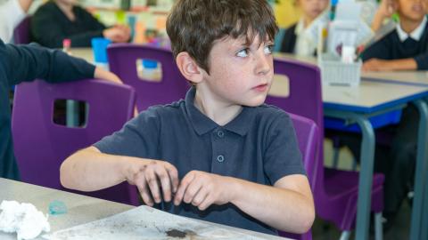A boy experiments with magnets and iron filings during a science lesson