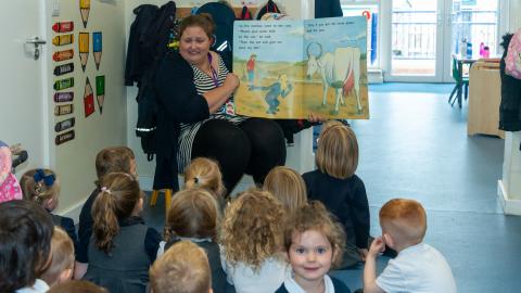 Story time for early years, a teaching assistant hold up the large picture book