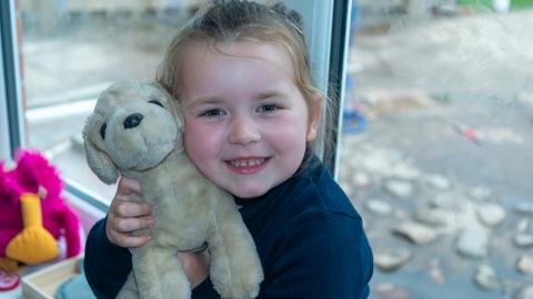 Young girl from early years holding a toy puppy